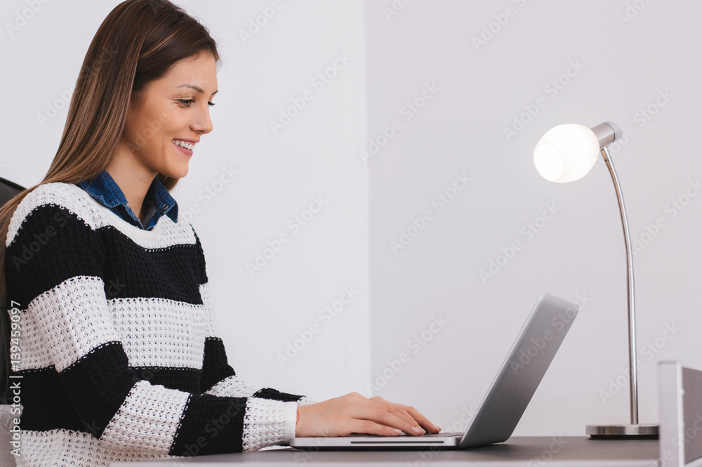 Pretty young student sitting at desk and doing her homework