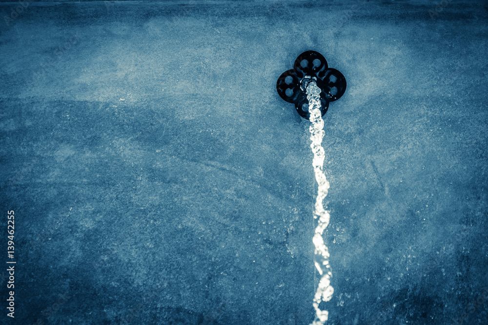 water flow from fountain from red wall cement decorstion pool with tree bokeh background