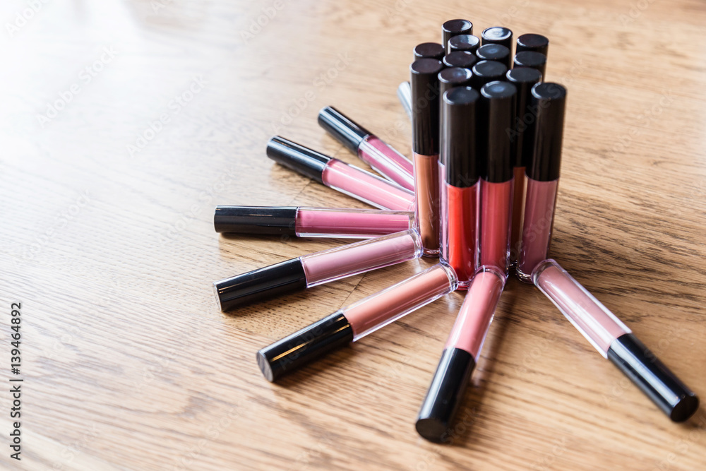 heap of bottle liquip lipstick on wooden table with free copyspace