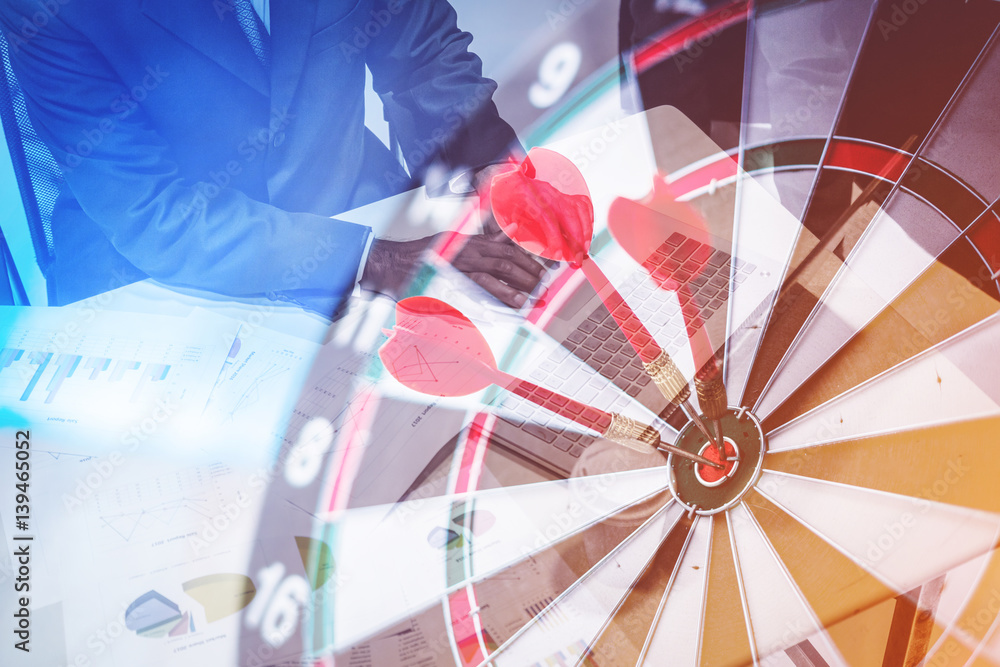 Red dart arrow hitting in the target center of dartboard with double exposure business man working w