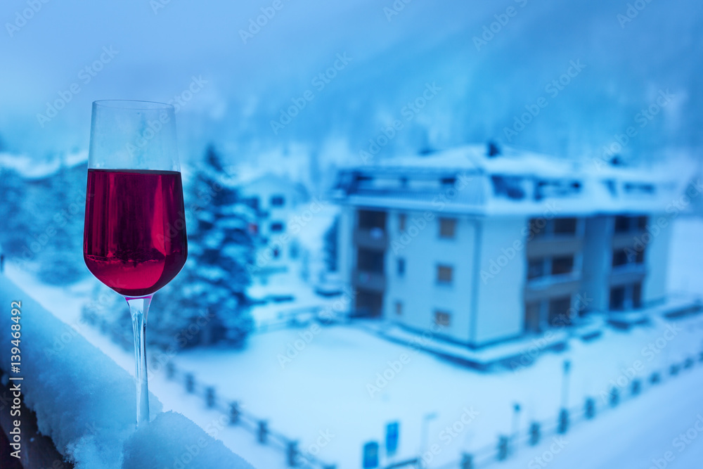 A glass of wine on snowcapped balcony balustrade