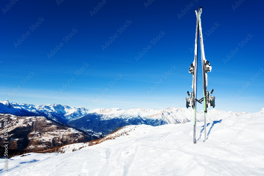 Skis stuck in snow bank against mountain scene