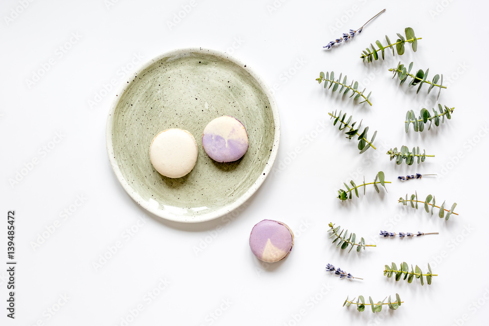 Trendy design with macaroons on plate, eucalyptus and lavander top view