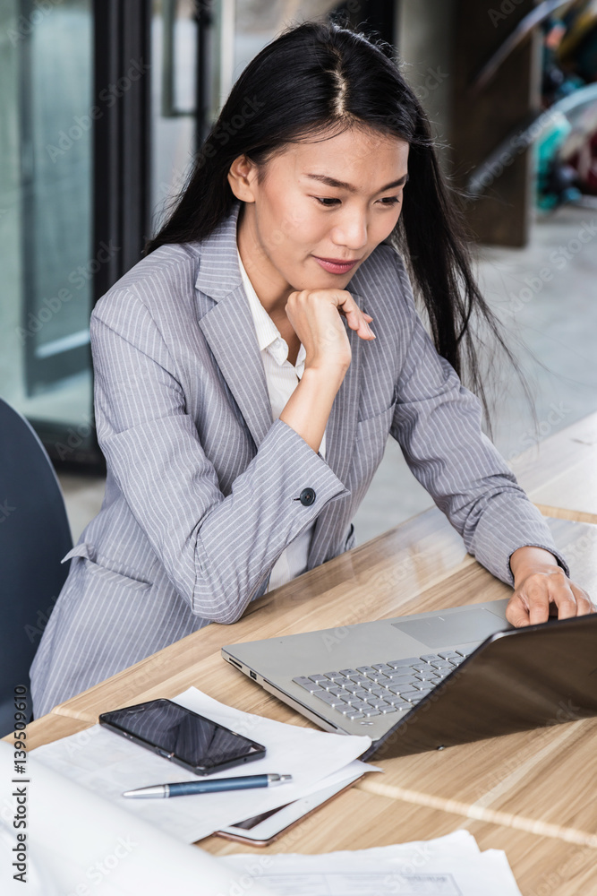 smart asian business woman working on table top with laptop paper coffee smartphone