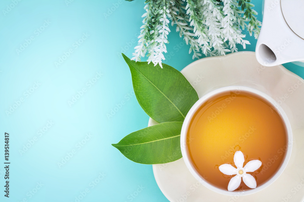 Top view shot of a hot cup of tea with green leaf and flower on blue background , Organic Tea ceremo