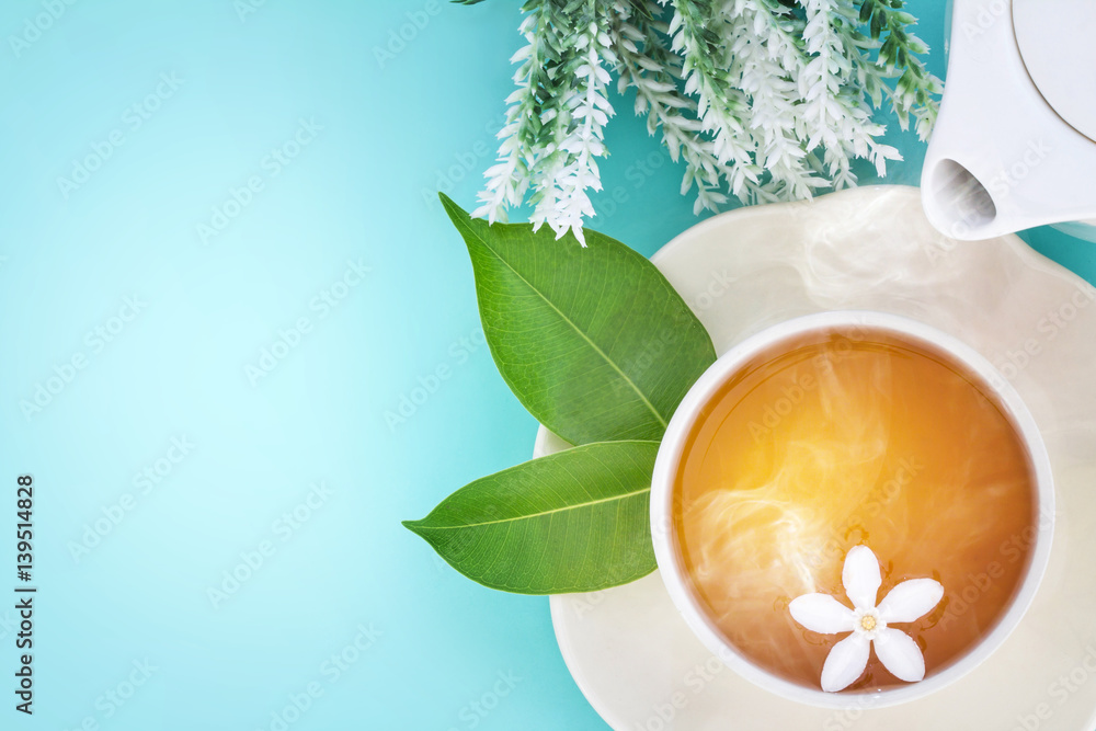 Top view shot of a hot cup of tea with green leaf and flower on blue background , Organic Tea ceremo