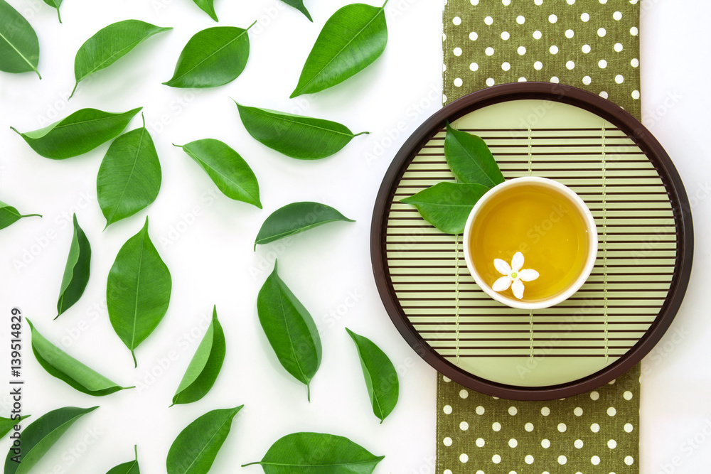 Top view shot of a hot cup of tea with green leaf decoration  on white background , Organic Tea cere