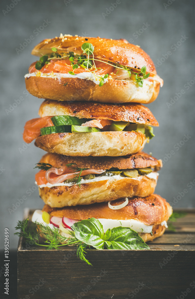 Heap of Bagels with salmon, eggs, vegetables, capers and cream-cheese, grey concrete background. Hea