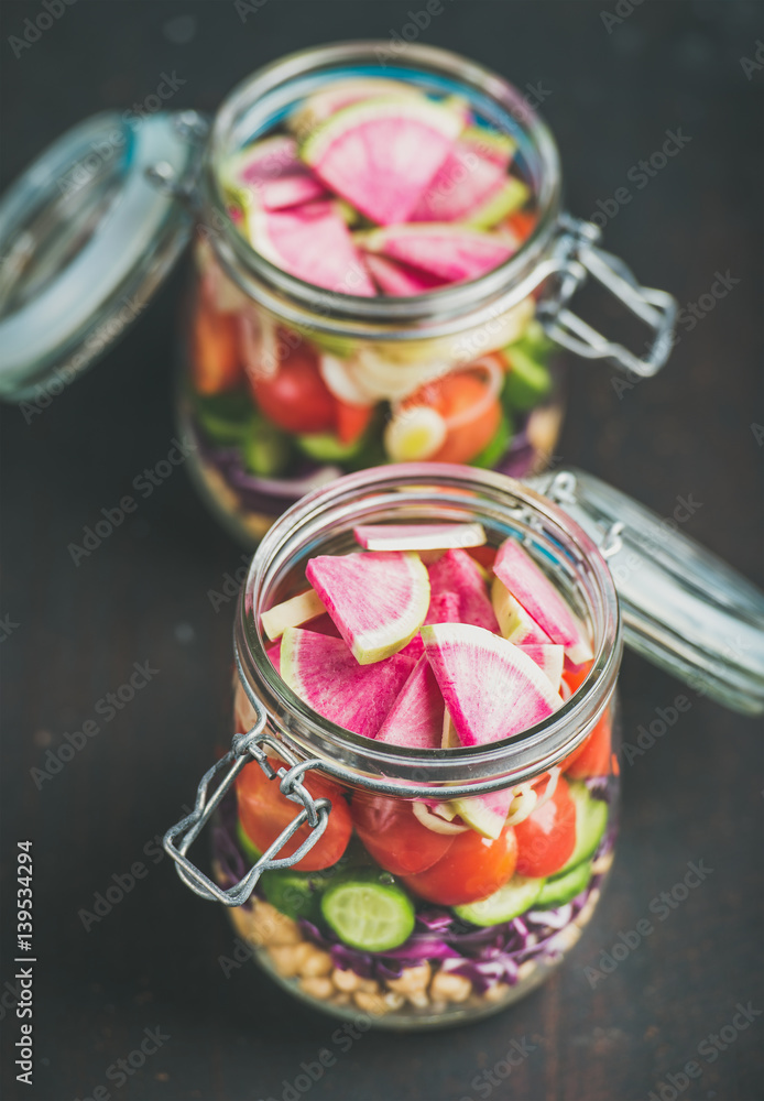 Healthy take-away lunch jars. Vegetable and chickpea sprout layered vegan salad in glass jars over d