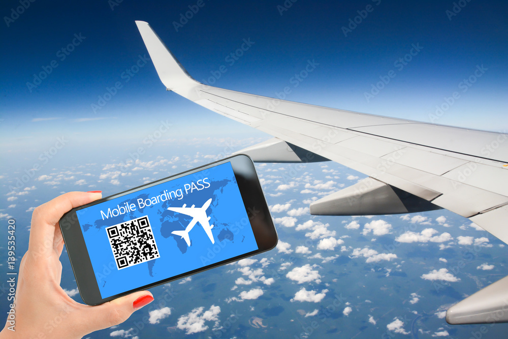 Mobile or electronic boarding pass on the screen of smartphone, with airplane wing in background