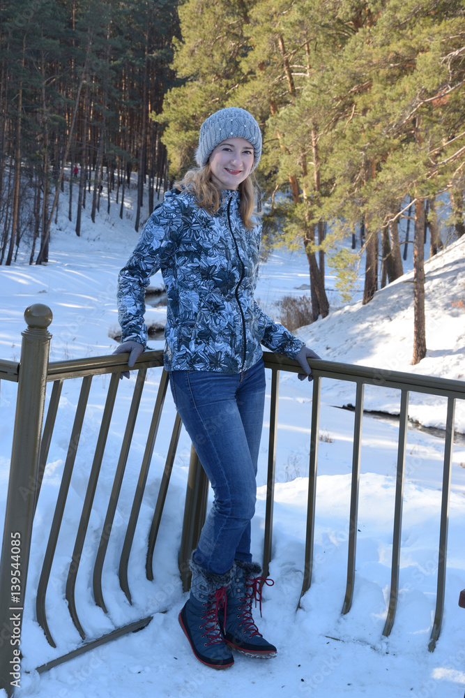 Sport girl in the forest standing on the bridge over the creek in early spring.