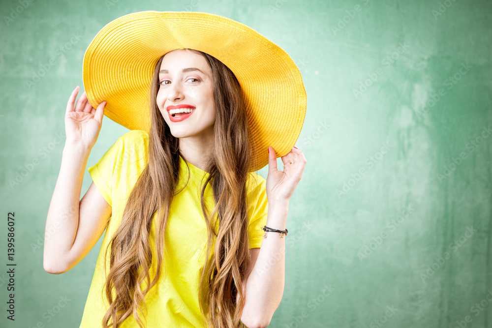 Colorful portrait of a beautiful woman in yellow t-shirt and hat on the green background