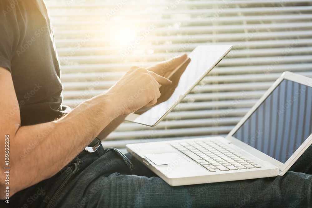 Business man works on digital tablet and laptop.