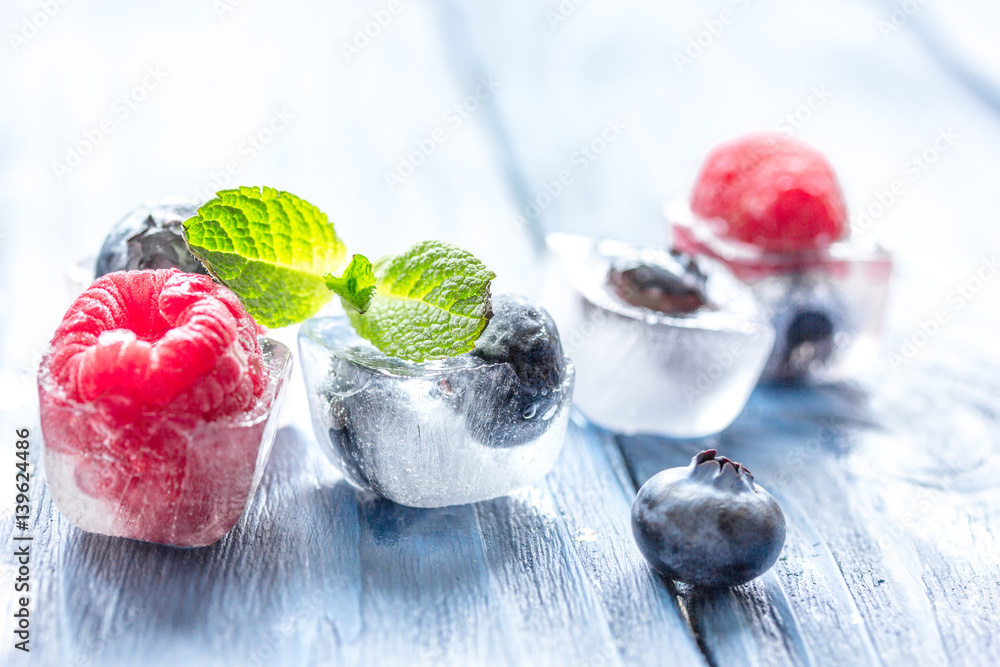 cubes of berry ice and mint leaf on wooden table beckground