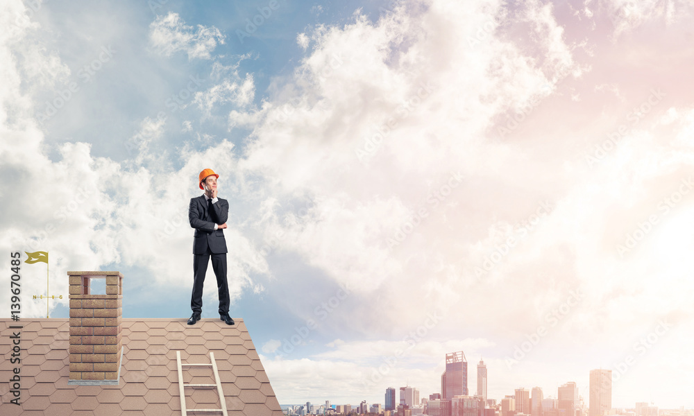 Engineer man standing on roof and looking away. Mixed media