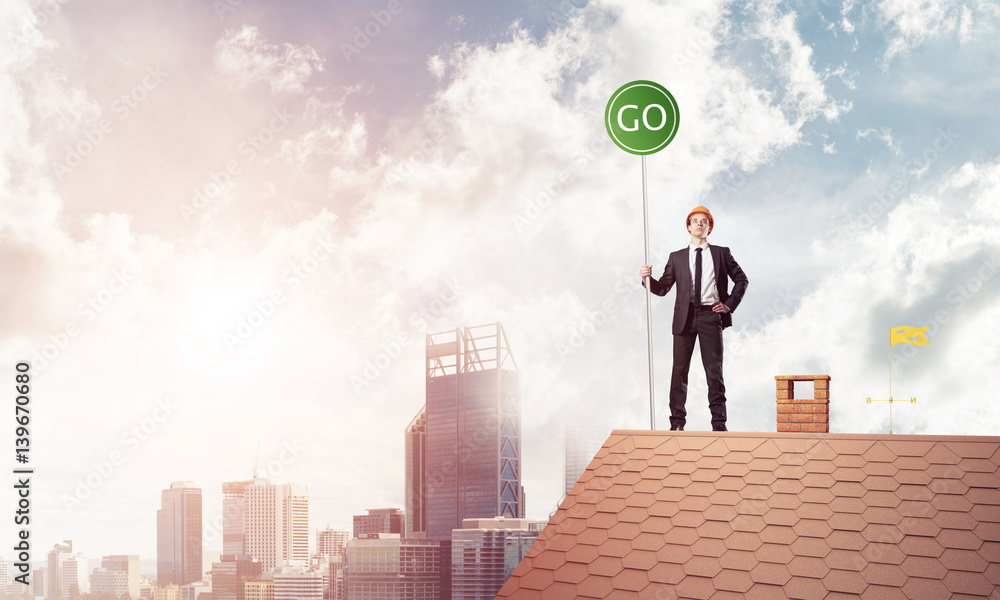 Businessman in suit on house top with ecology concept signboard.