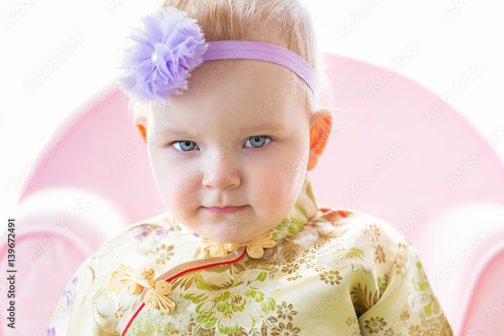 Little caucasian girl posing in oriental outfit