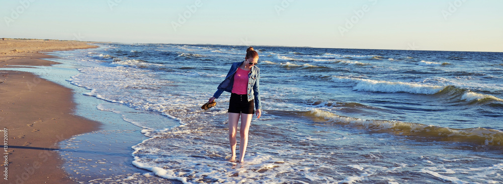 junge Frau spaziert barfuß in der Nordsee