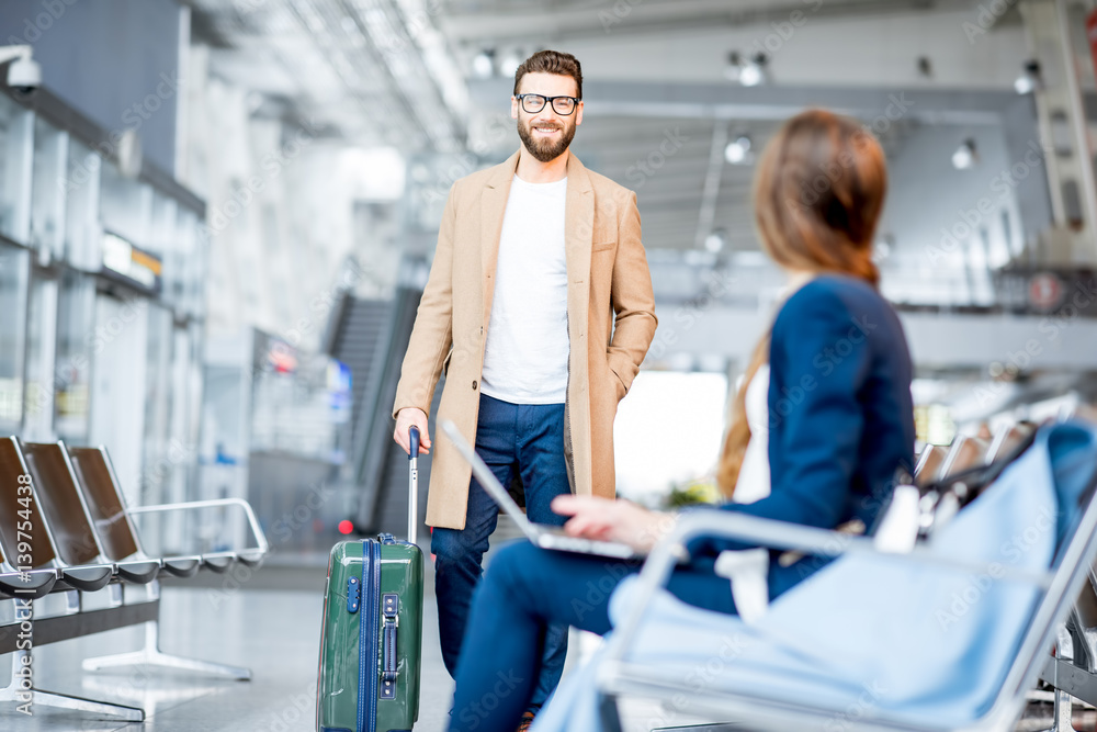 Elegant businessman in the coat meeting businesswoman at the waiting hall of the airport