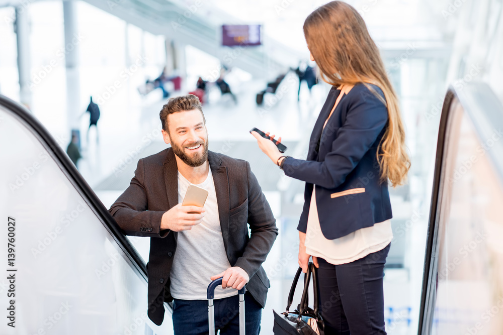 Business couple talking on the escalators at the airport