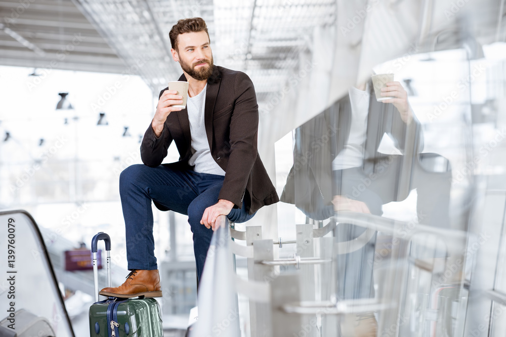 Businessman waiting with coffee to go at the airport. Business travel concept