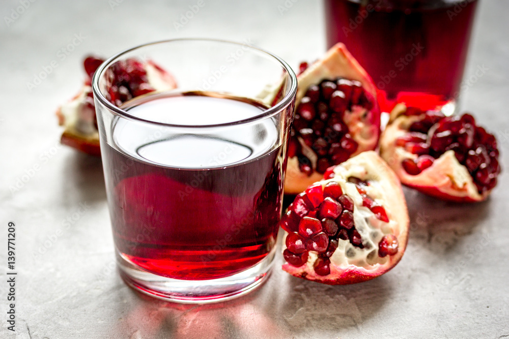 fresh pomegranate with juice in glasses on kitchen background