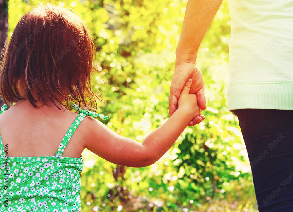 Toddler girl holding hands with her mother