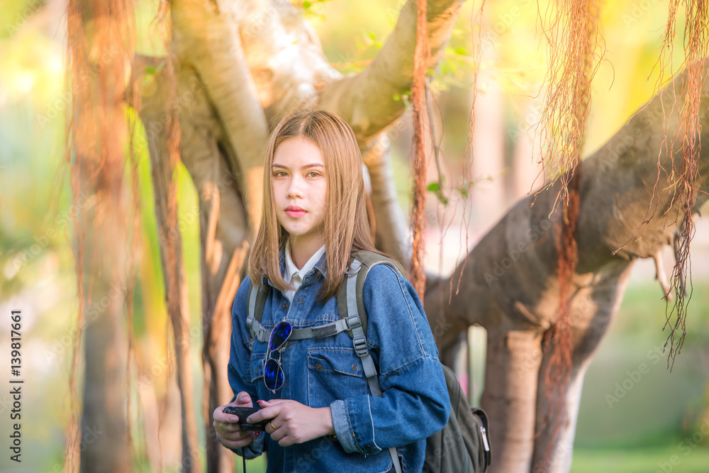 Outdoor fashion portrait traveler of stylish photographer girl holding camera, wearing jeans jacket,