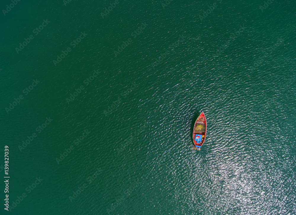 Fishing boat floating in the sea. The beautiful bright blue water in a clear day.Aerial view.Top vie