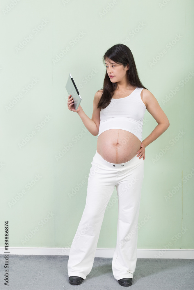 young pretty pregnant woman with tablet