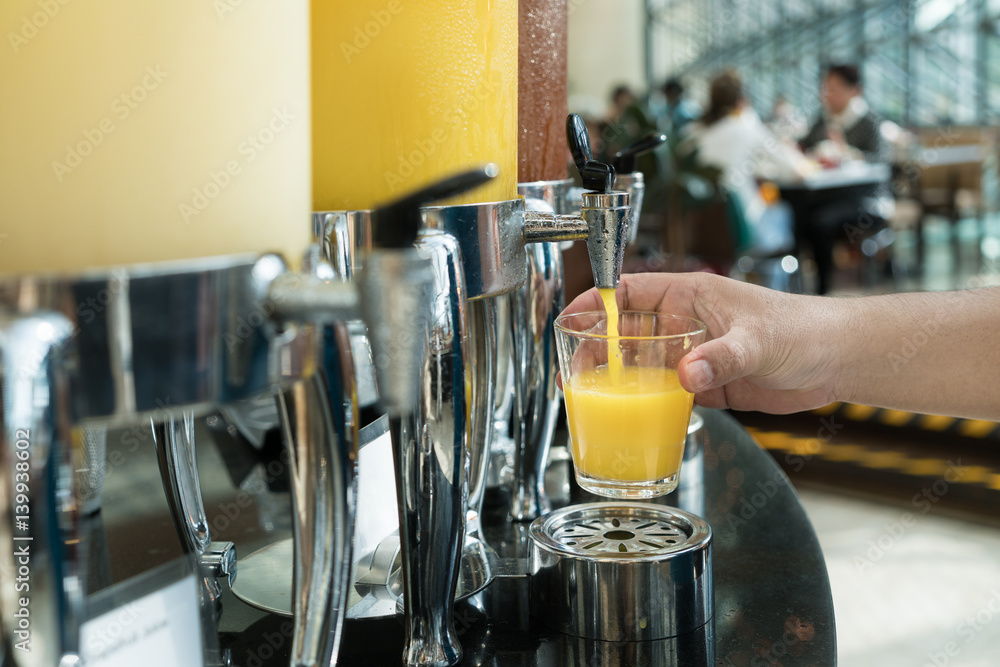 Hand holding glass refill orange juice for row of fresh juice at buffet restaurant, Juice buffet sel