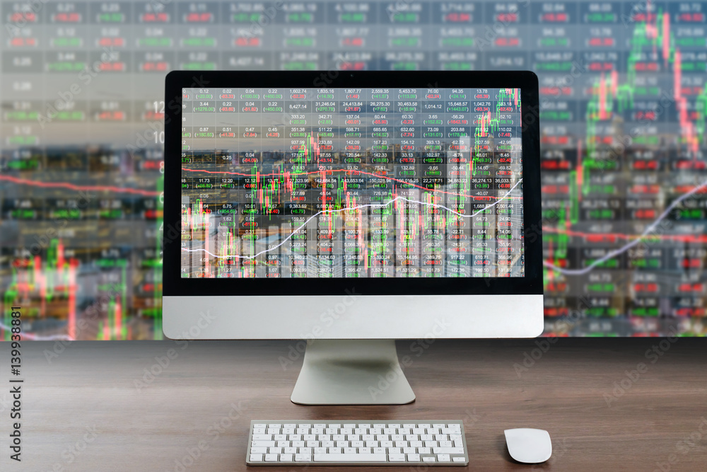 Business computer on wood table showing business trading graph with cityscape building in background