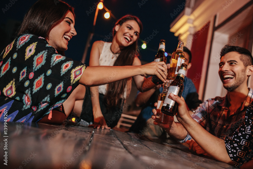 Group of friends toasting drinks at party in evening