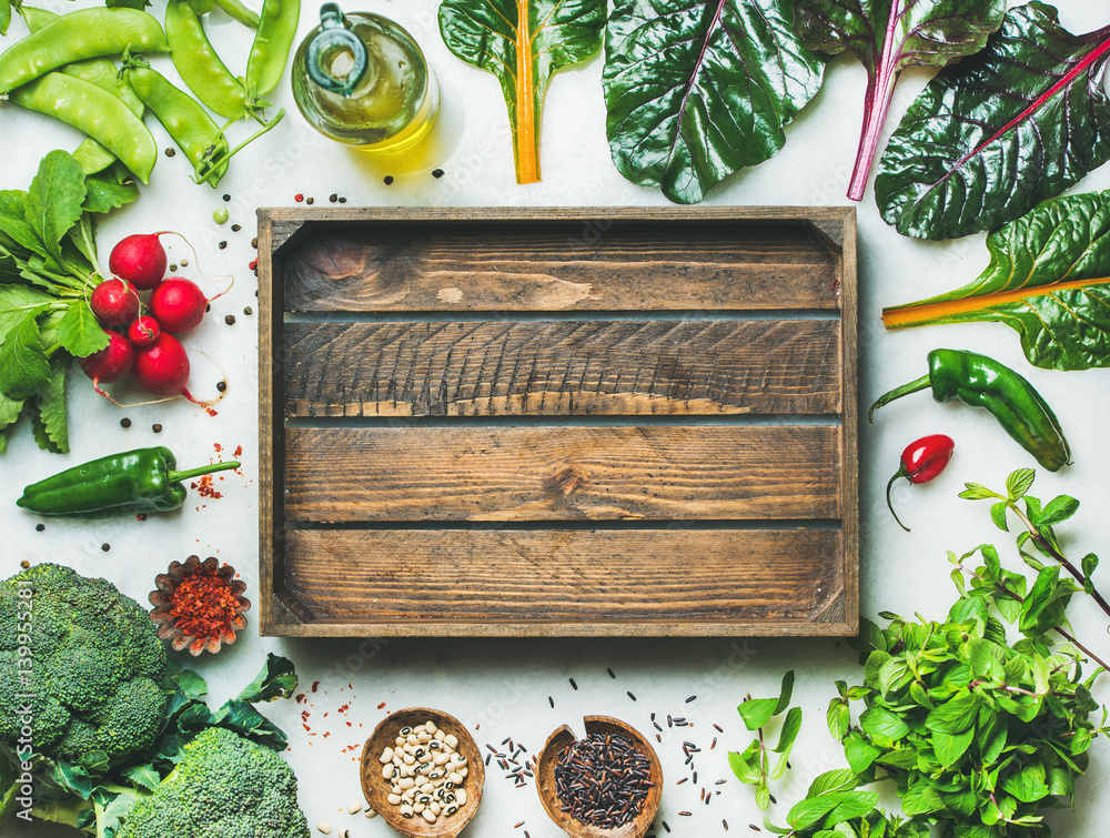 Fresh raw greens, unprocessed vegetables and grains over light grey marble kitchen countertop, woode