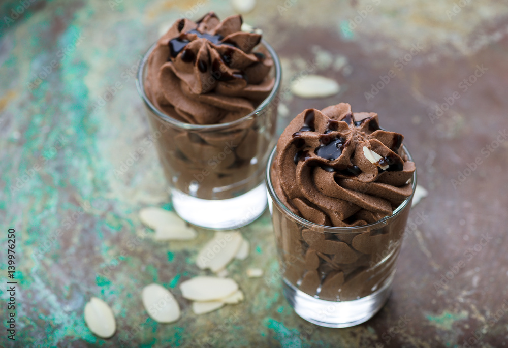 Chocolate mousse with chocolate sauce and almond slices in a glasses on a vintage background.