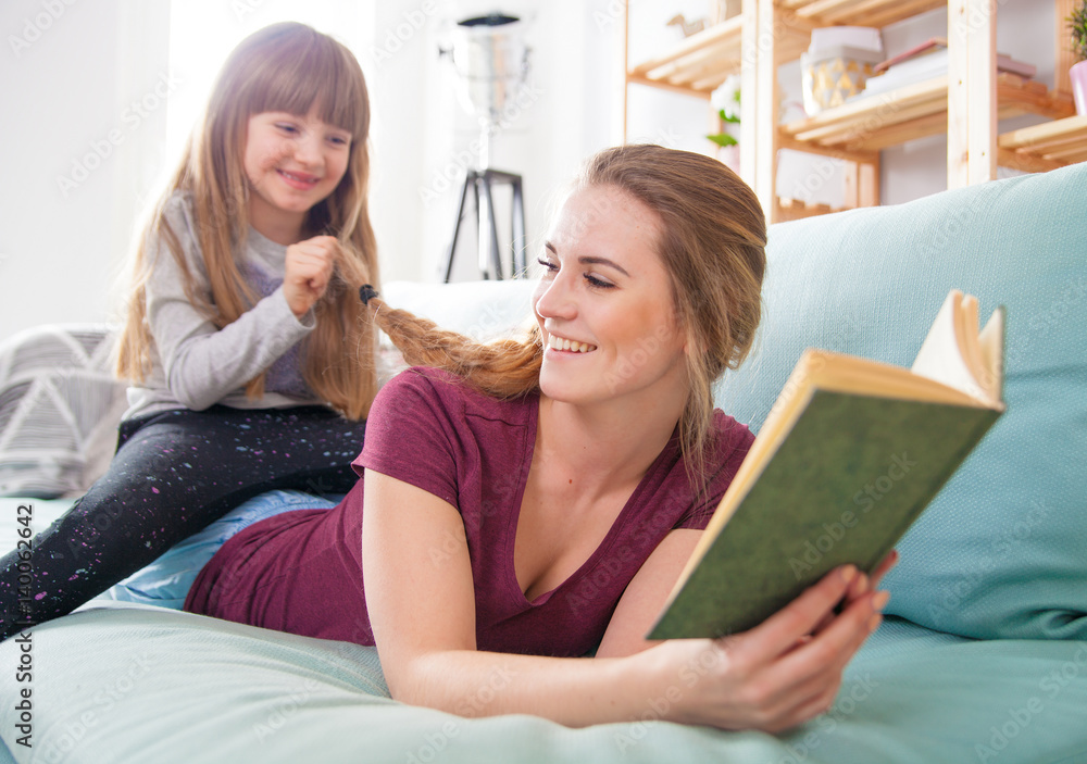 Mother and daughter sitting on sofa and playing together