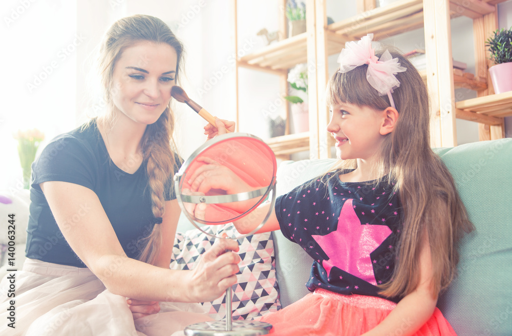 Mother and daughter playing and doing makeup, family at home