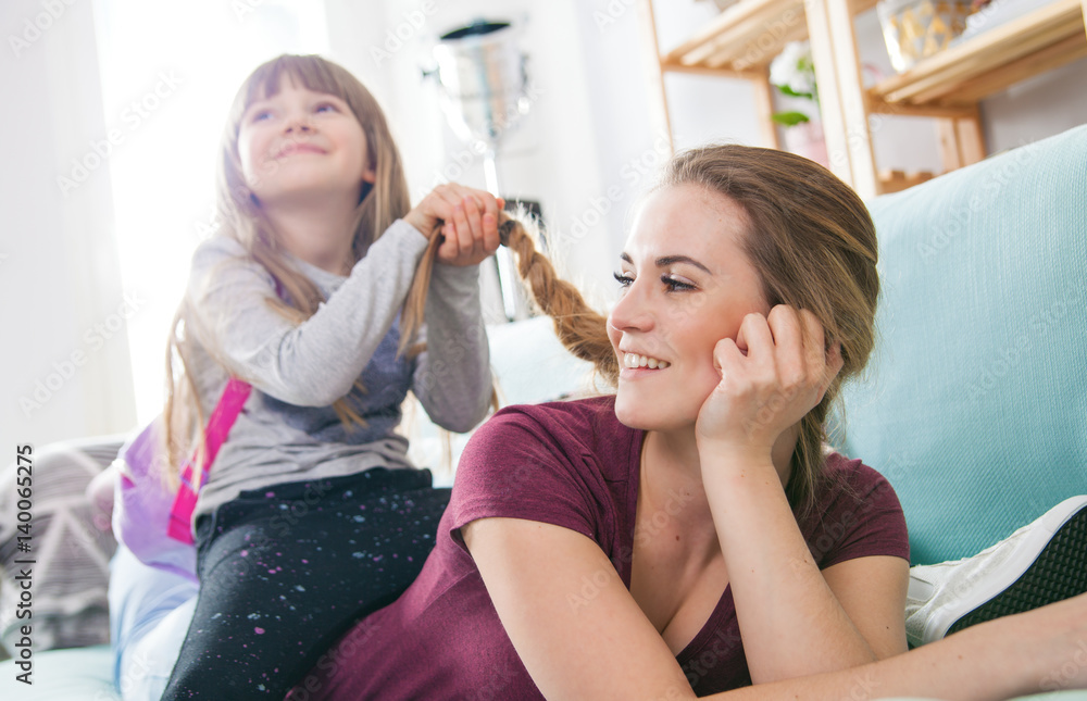 Daughter braiding mothers long hair, happy loving family