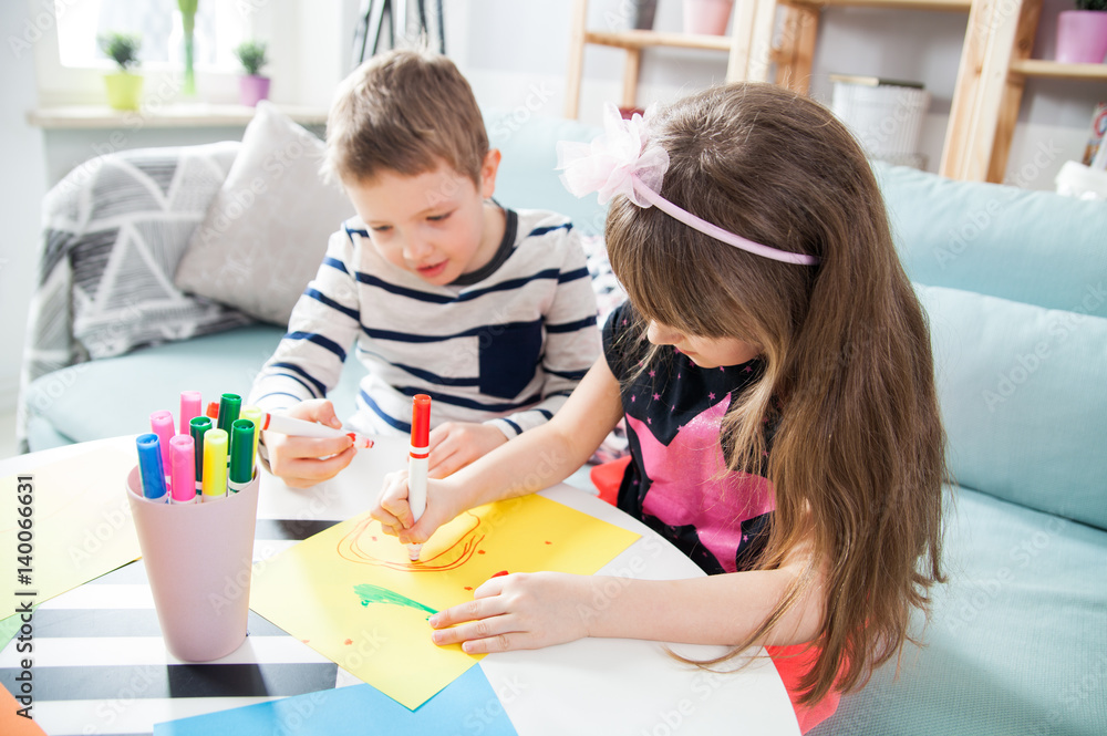 Brother and sister drawing with colorful pencils at home