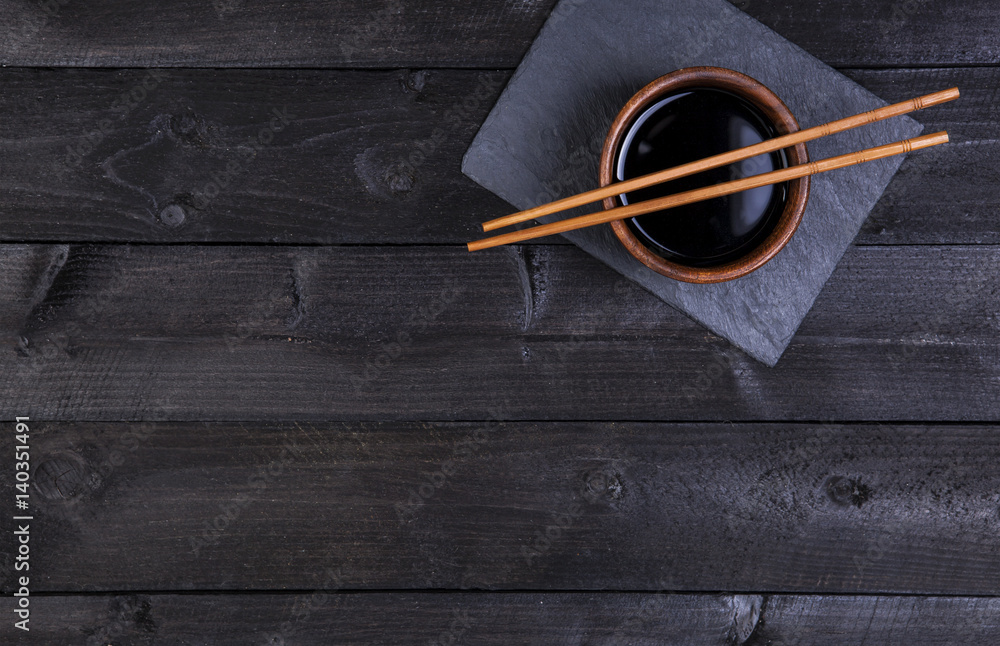 Background for sushi. Soy sauce, chopsticks on black stone. Top view with copy space