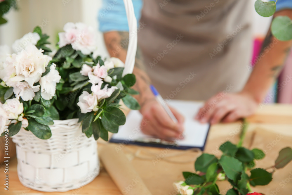 Wicker basket with white azalea flowers on florist table