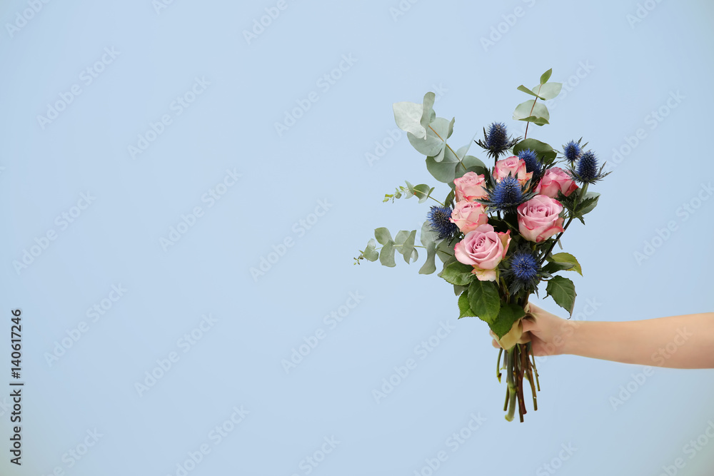 Female hand holding beautiful bouquet on light background