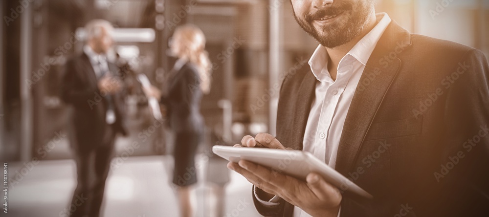 Businessman using digital tablet in office corridor