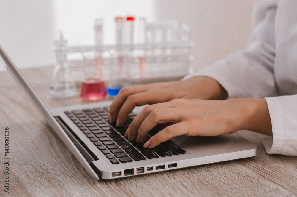 Close-up of female doctor typing laptop sitting at a table in the hospital