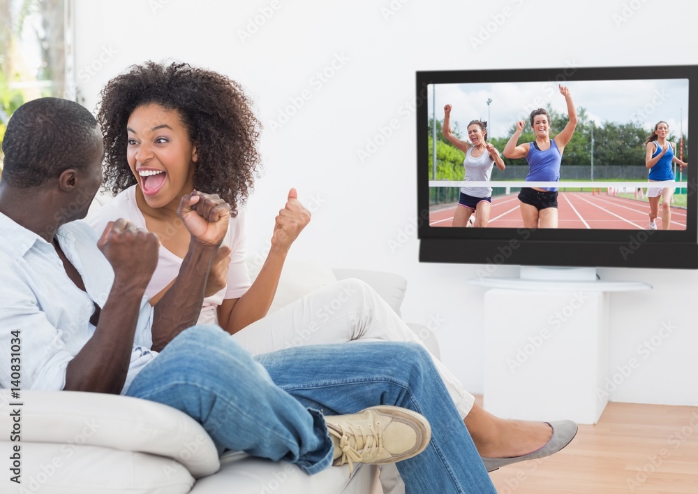 Excited couple cheering and watching a sports in television