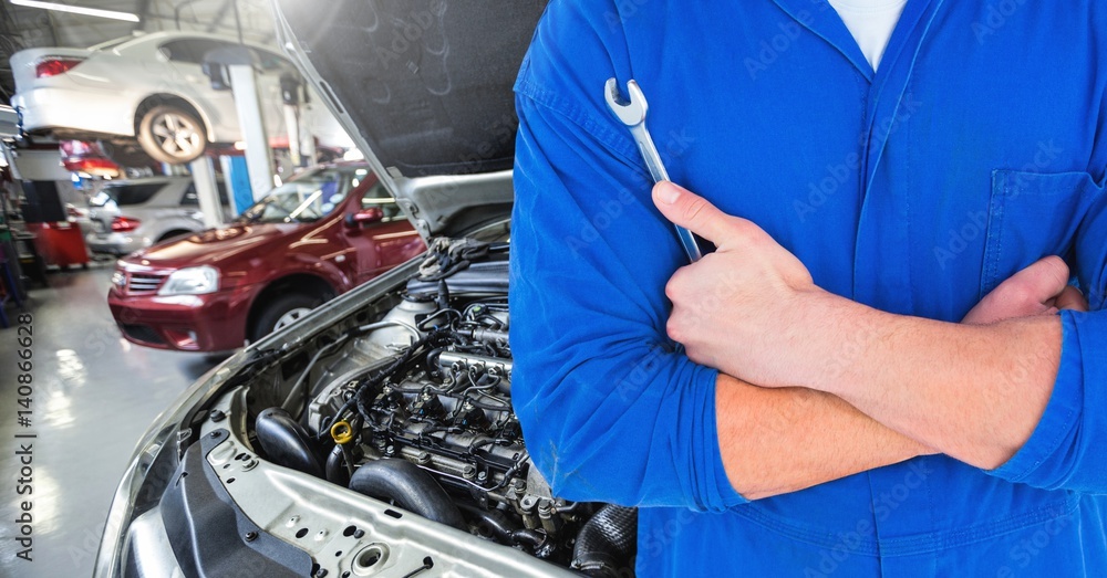 Mid section of automobile mechanic holding a wrench in workshop