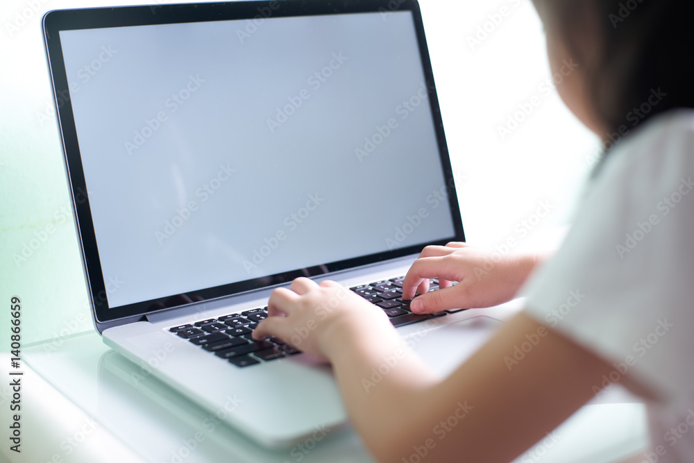 Kid using laptop with white copy space screen .