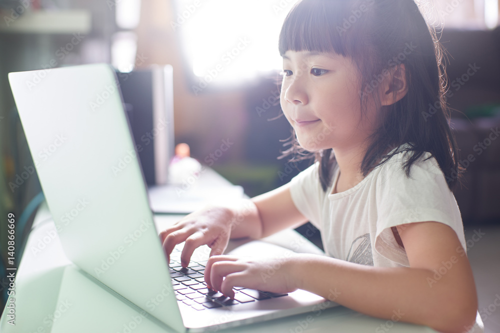 Little asian girl  using laptop to studying . selected focus on eye with blurred background .