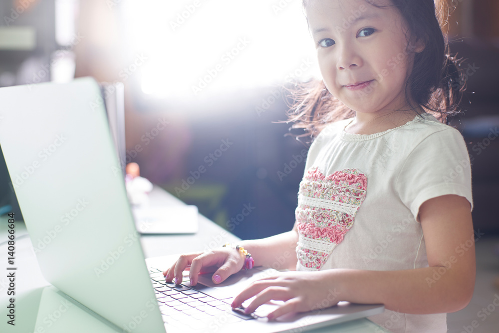 Little asian girl enjoy using laptop to studying .