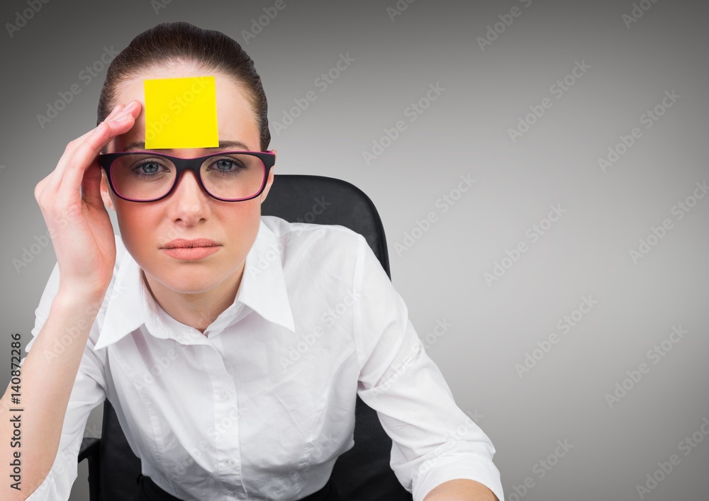 Serious businesswoman with sticky note on her forehead